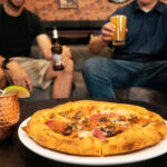 Pizza and moscow mule with two men holding beers